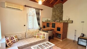 A living room with a wooden ceiling, a brick fireplace, a sofa, a coffee table, and a stone wall.
