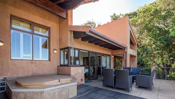 A modern outdoor patio with a hot tub, seating area, and outdoor furniture.