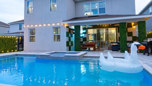 A modern house with a swimming pool, outdoor seating, and string lights.