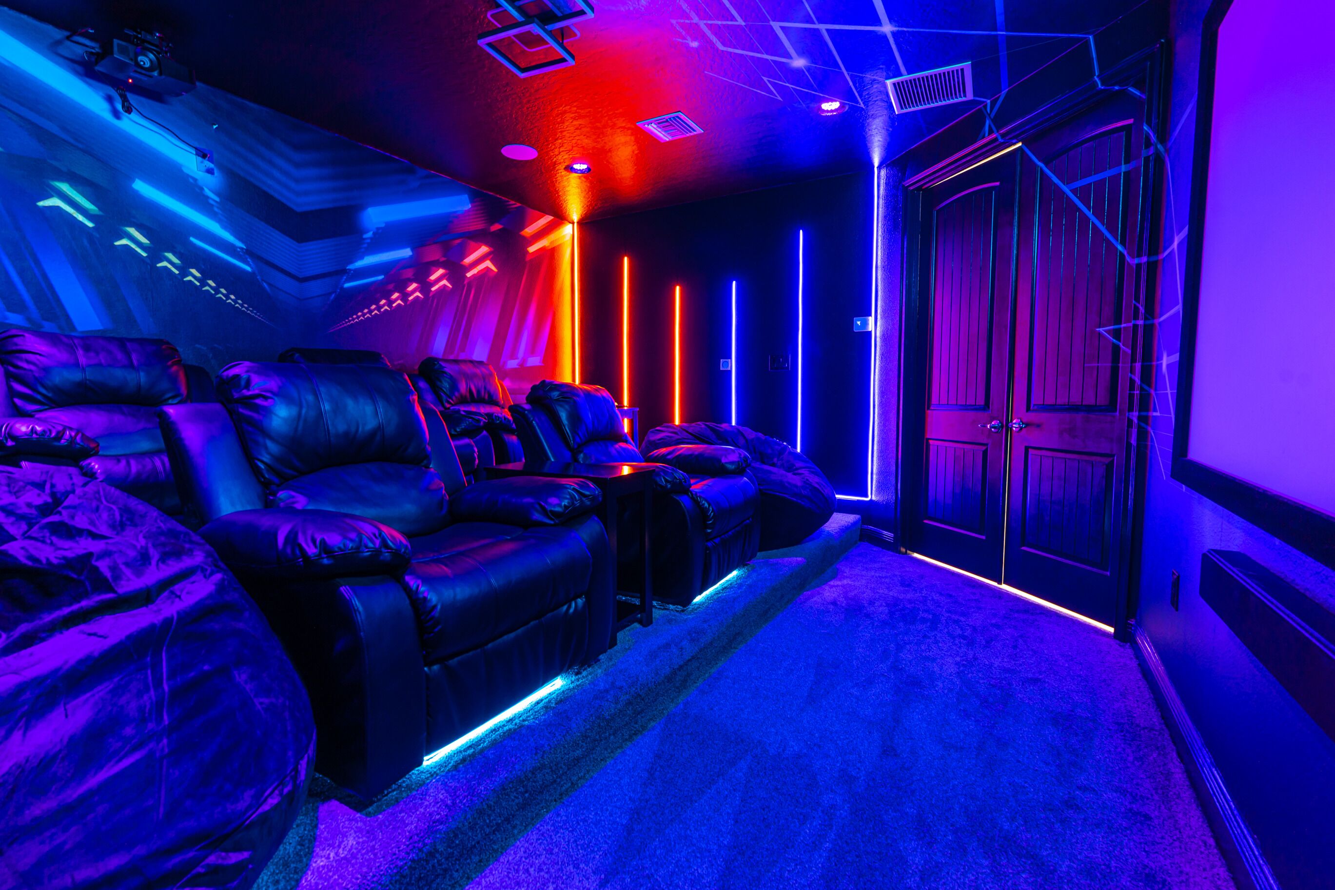 A room with a leather sofa, a door, and neon lights.