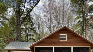 Une cabane en bois avec une grande fenêtre et une table de pique-nique devant.