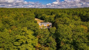 A house surrounded by dense forest with a clear sky. - WATERFRONT ON LONG LAKE  (HARRISON)