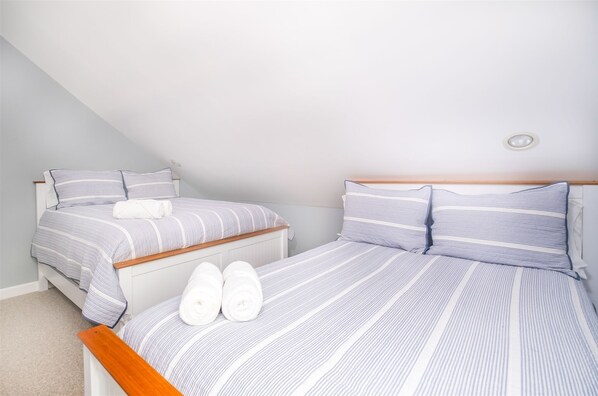 A bedroom with two beds, each with striped bedding and white towels.