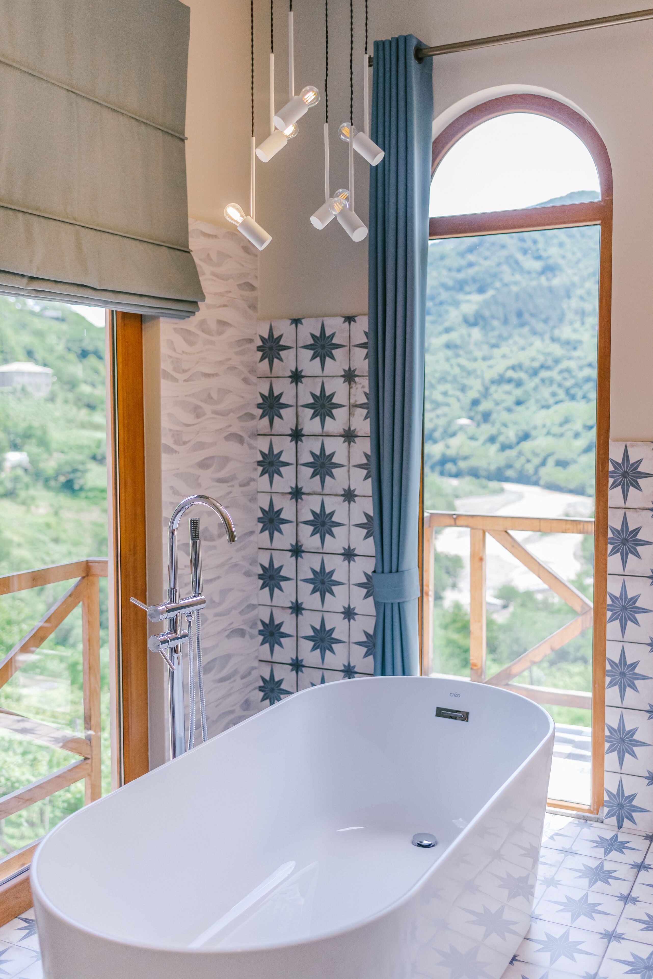 Een badkamer met een vrijstaand bad, een douche en een raam met uitzicht op een bergachtig landschap.