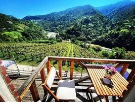 Una terraza de madera con una mesa y sillas, con vistas a un viñedo.