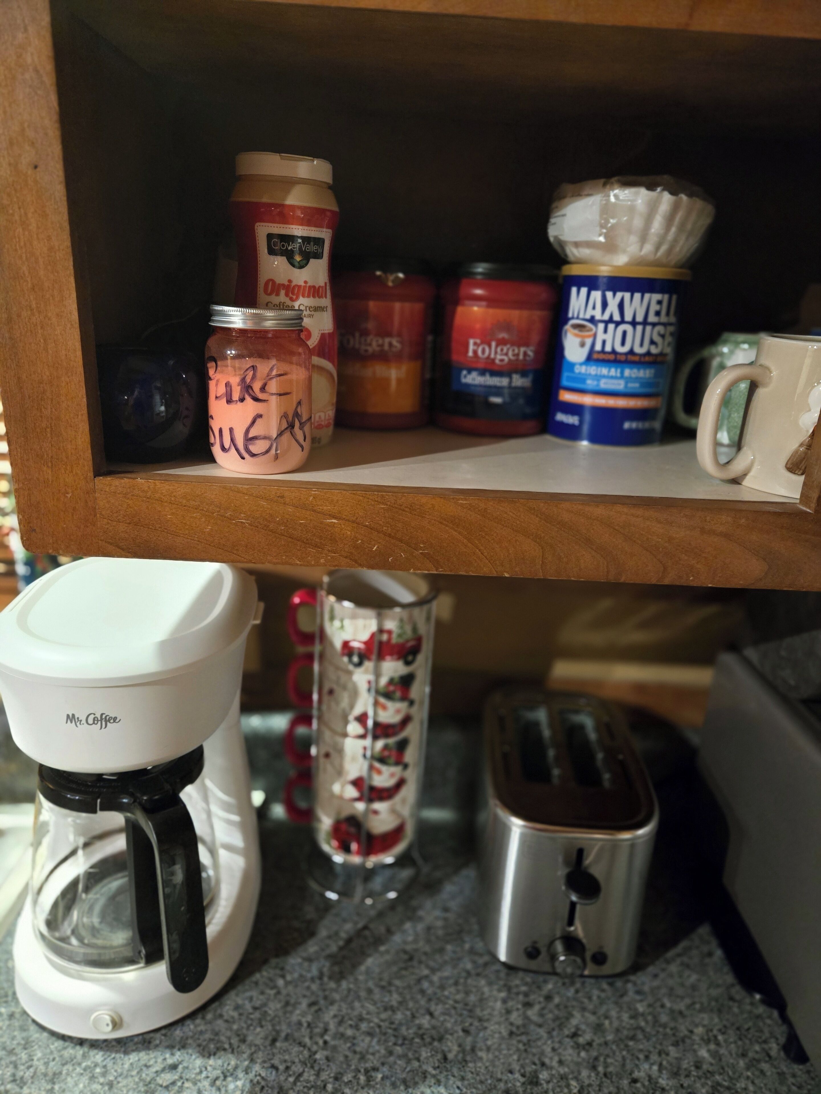 Una repisa de cocina con diversos productos de café, incluyendo tarros de leche para café y café Folgers.