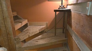 Eine Holztreppe mit Holzwandlaufung und ein kleiner Tisch mit einer Lampe oben.