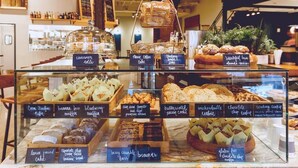 Eine Bäckereiauslage mit verschiedenen Backwaren, darunter Zimtschnecken, Kaffeekuchen und Frühstücksbrötchen.