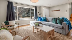 Un salon moderne avec un canapé gris, une table basse en bois et une grande fenêtre avec des rideaux.