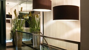 A modern interior with a glass railing, potted plants, and two hanging lamps. - HOTEL SALUS (Pescara)