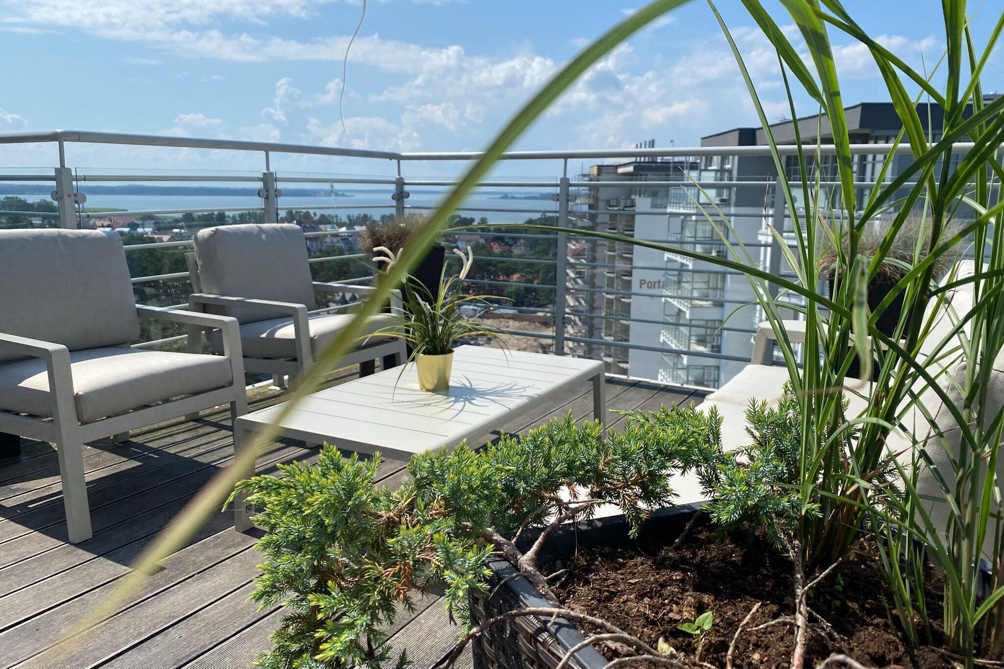 Een balkon met zitplaatsen, plantenbakken en uitzicht op de stad.