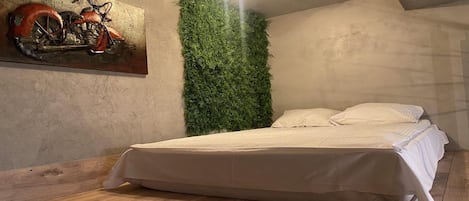 Un dormitorio con una cama, una lámpara de pared, un mapa y una motocicleta.