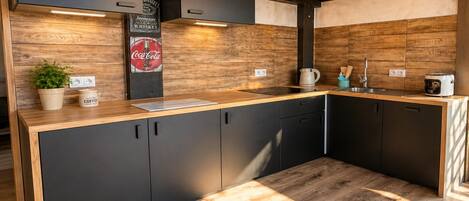 Una cocina moderna con armarios oscuros, encimera de madera y estufa integrada.