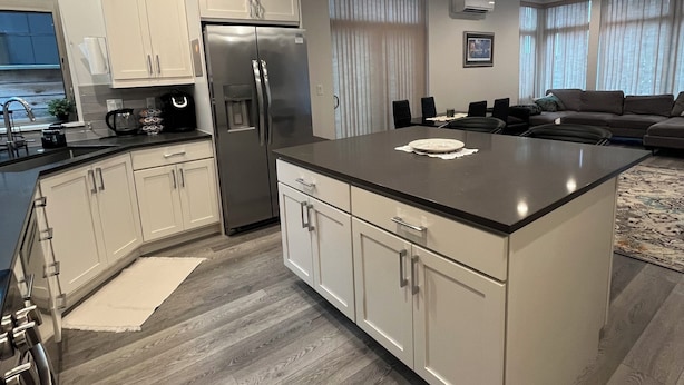 A modern kitchen with white cabinetry, a stainless steel refrigerator, and a large island. - Bright Townhome in Trendy Ballard (Seattle)