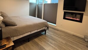 A bedroom with a bed, a TV mounted on the wall, and a fireplace. - Bright Townhome in Trendy Ballard (Seattle)