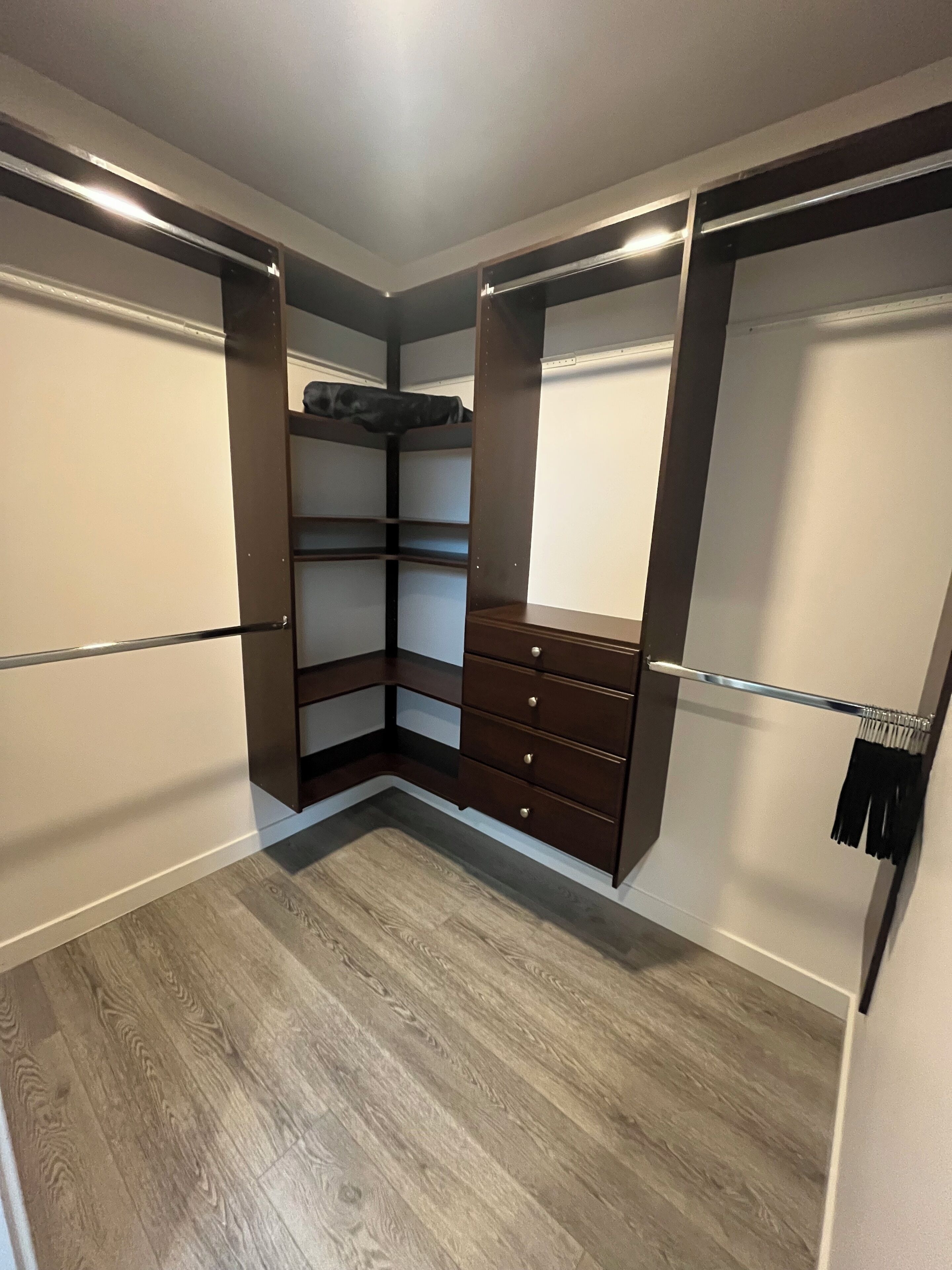 A walk-in closet with built-in shelves, drawers, and a hanging rod.
