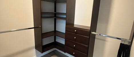 A walk-in closet with built-in shelves, drawers, and a hanging rod.
