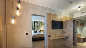 Moderni huone, jossa on sänky, puiseen seinään asennettu televisio ja pieni pöytä.