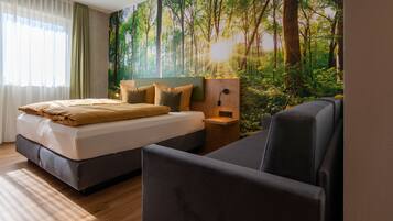Un dormitorio con cama, mesita de noche, lámpara de pared y un mural grande con un bosque.