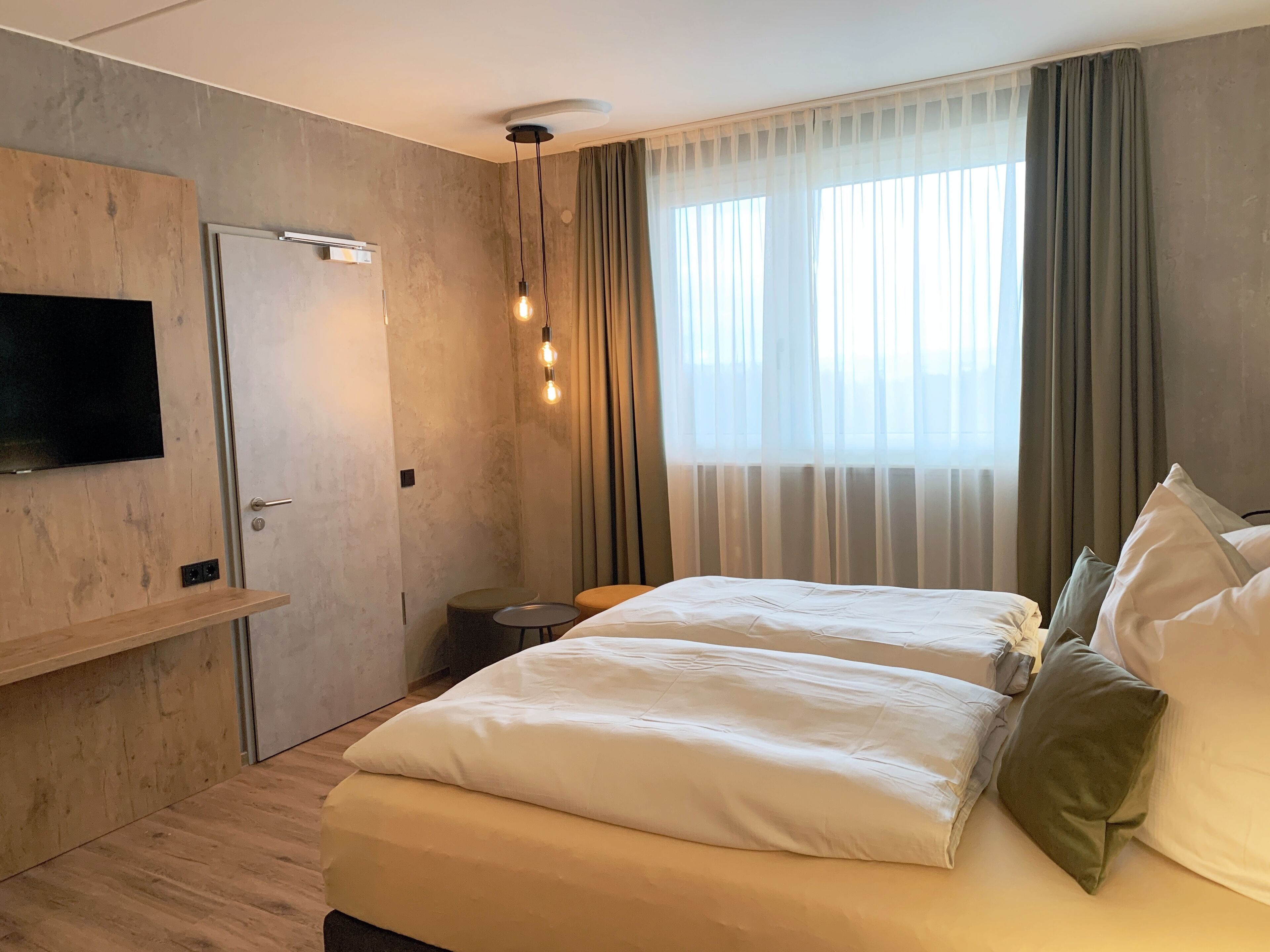 Een moderne hotelkamer met een groot bed, een aan de muur bevestigde televisie en een plafondlamp.