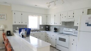 Een moderne keuken met witte kasten, een centraal eiland, een spoelbak en een kookplaat.