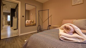 A bedroom with a bed, a large mirror, a standing lamp, and a bedside table. - Bellerose 2 (Lancaster)
