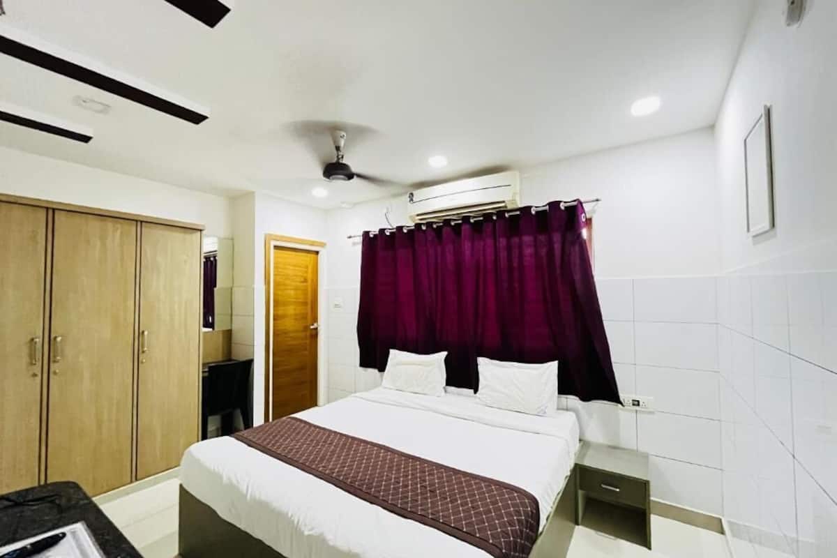 A hotel room with a bed, a wardrobe, a desk, and a ceiling fan.