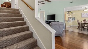 A staircase leading to a living area with a television, dining table, and chairs.