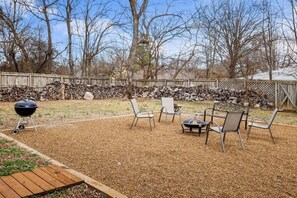 A backyard with a barbecue grill, fire pit, and outdoor seating area. - 4BR Game-Day Retreat - Foosball & Fire Pit (Fayetteville)