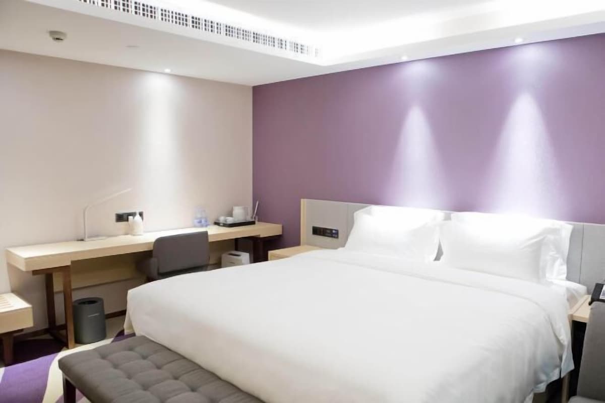 A hotel room with a large bed, a desk, and a chair.