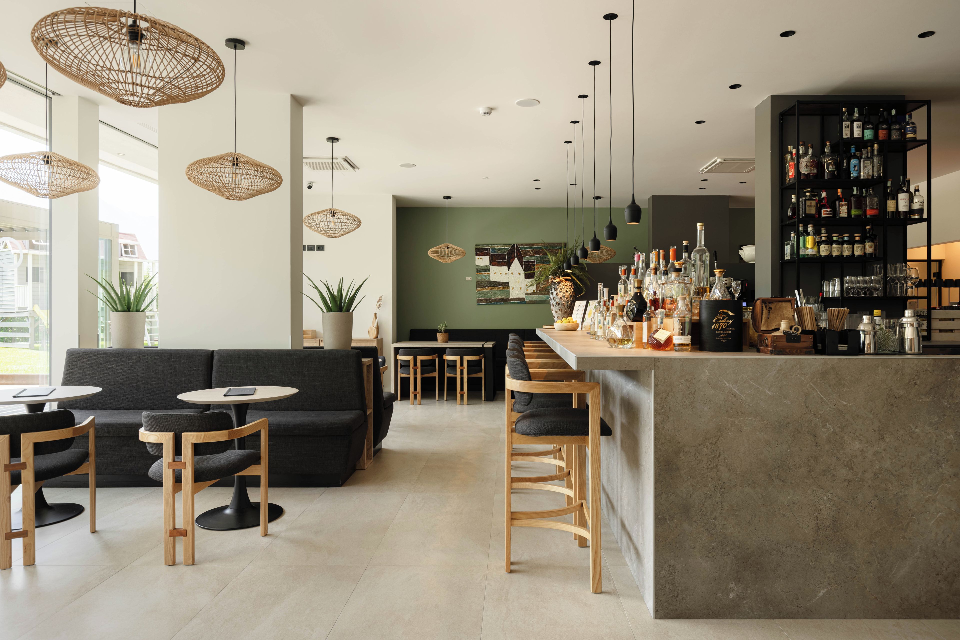 A modern bar area with a bar counter, seating, and a variety of bottles.