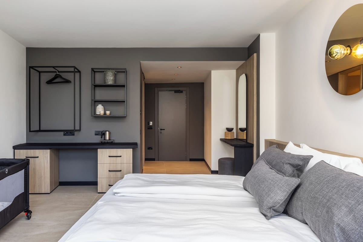Une chambre d’hôtel moderne équipée d’un lit, de tables de chevet, d’un bureau et d’une armoire.