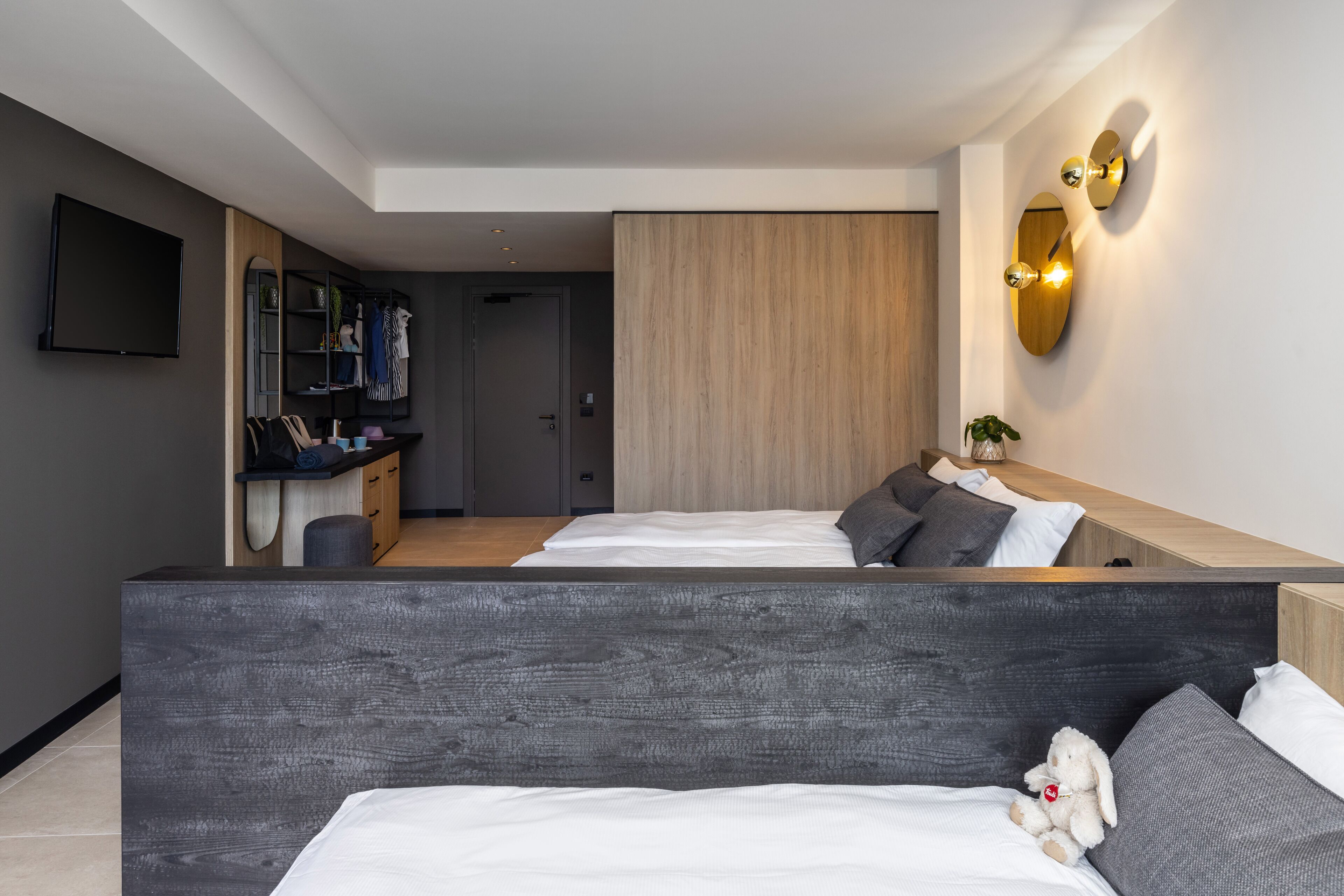 A modern hotel room with a large bed, a desk, and a TV.