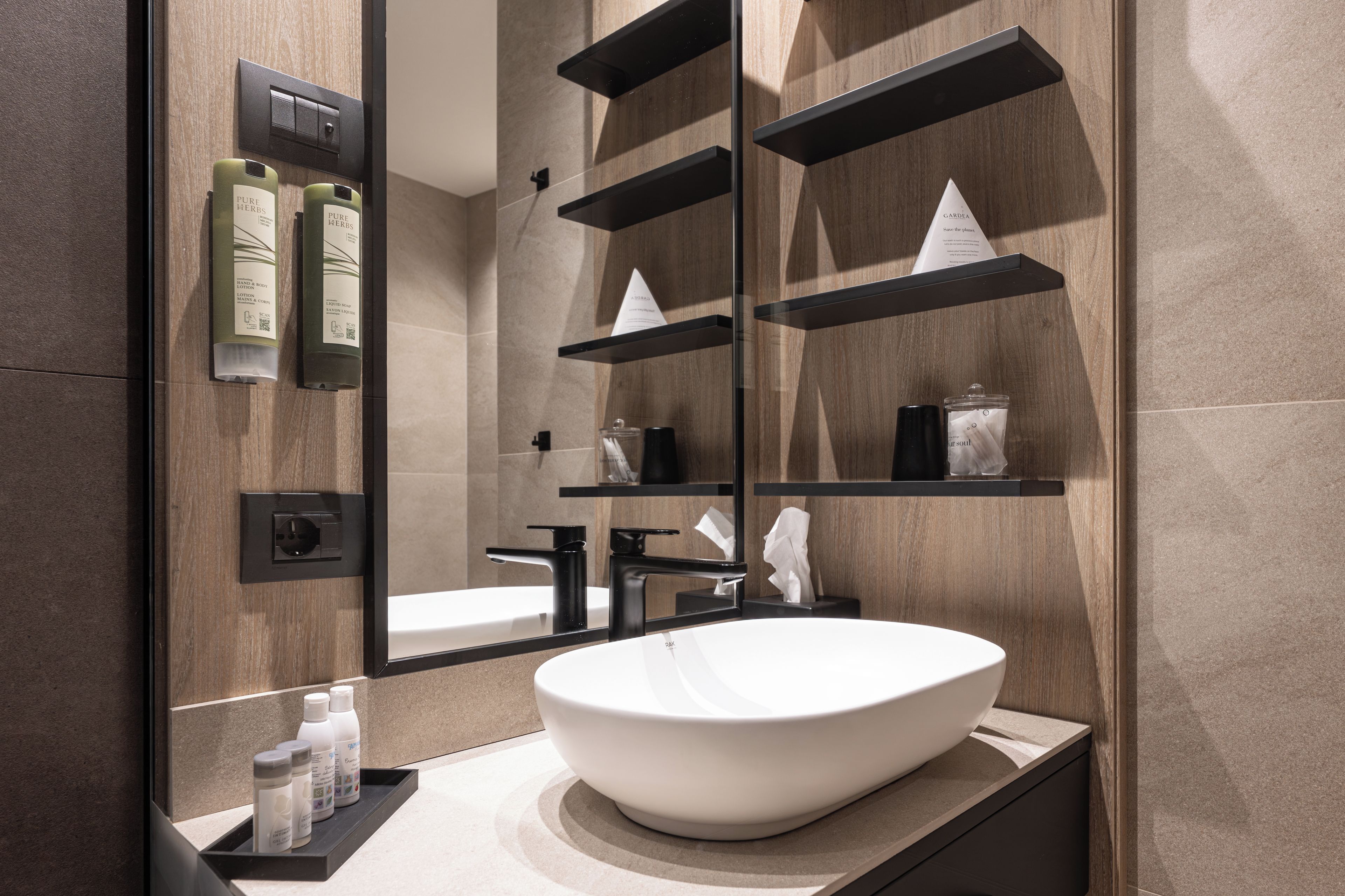 Une salle de bain moderne avec un grand miroir, un lavabo sur colonne blanc et un meuble-lavabo en bois.