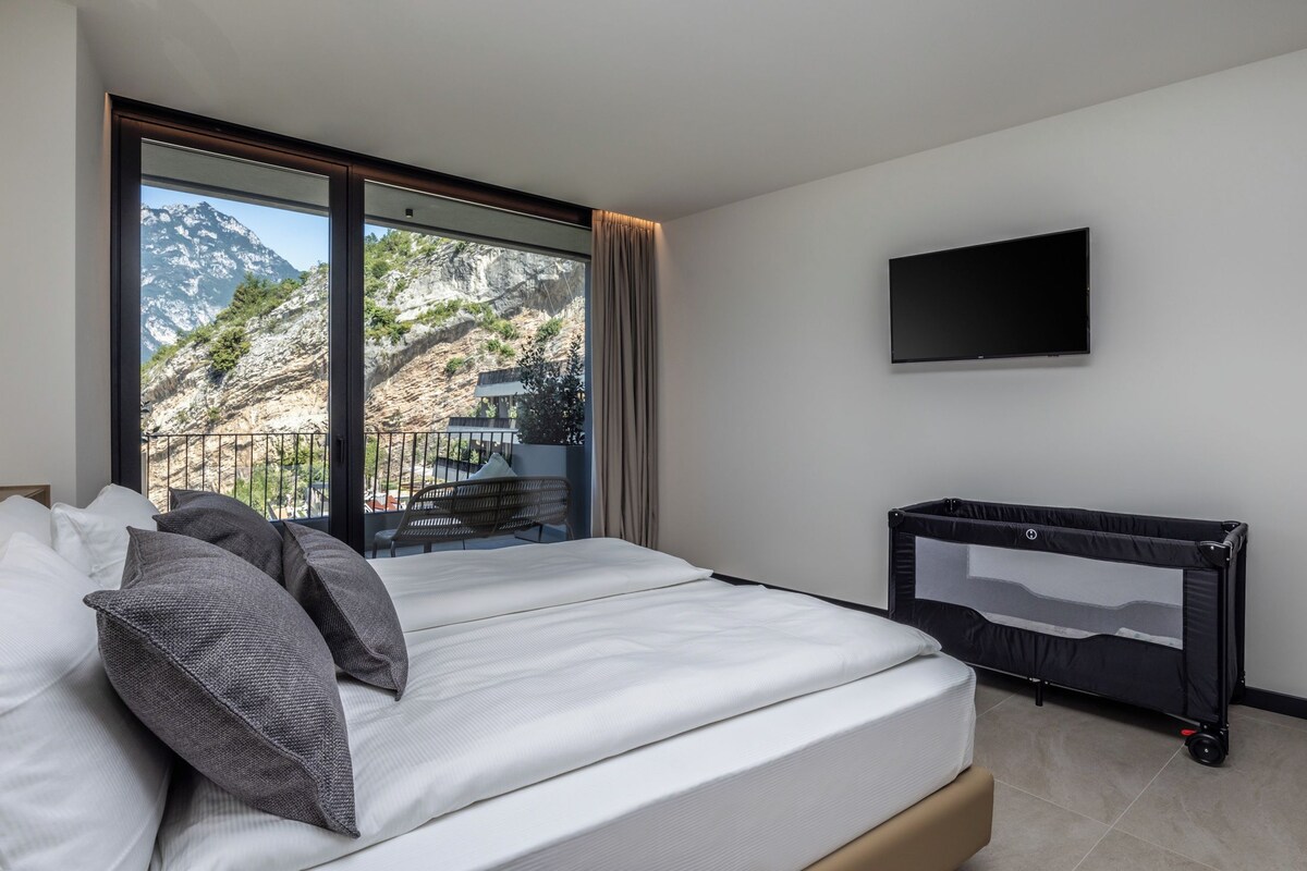 Quarto de hotel com cama, televisão e vista para montanhas.