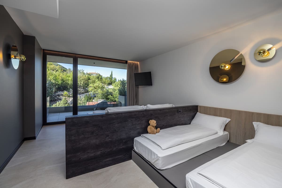 Une chambre d’hôtel moderne dotée d’une grande fenêtre, d’un lit, d’une table de chevet, d’un téléviseur et d’un luminaire fixé au mur.