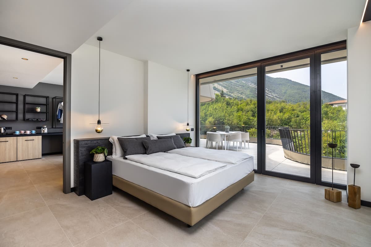 Une chambre moderne avec un grand lit, une vue sur l’extérieur et un coin cuisine.