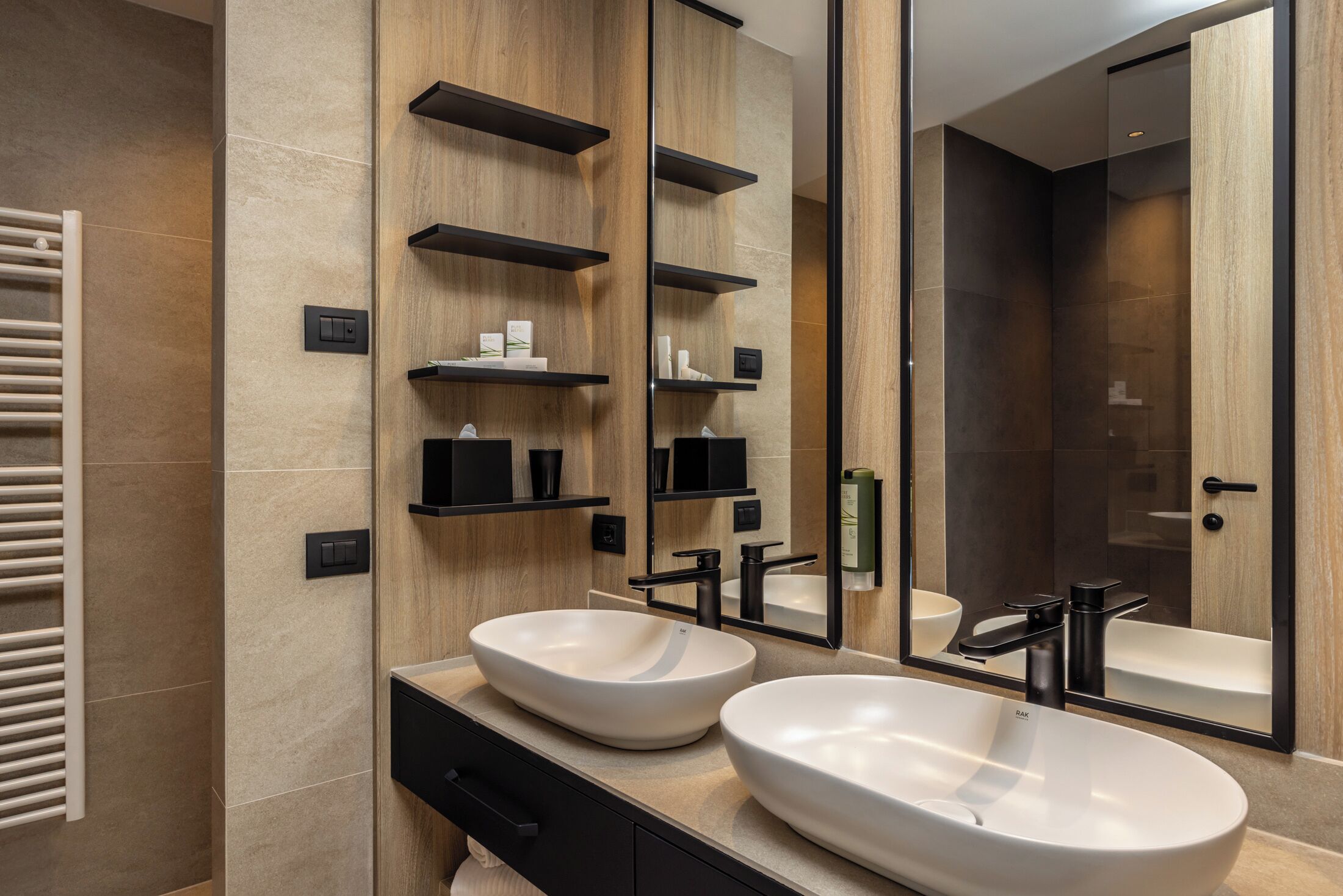 A modern bathroom with two large white sinks, a mirror, and built-in shelves.