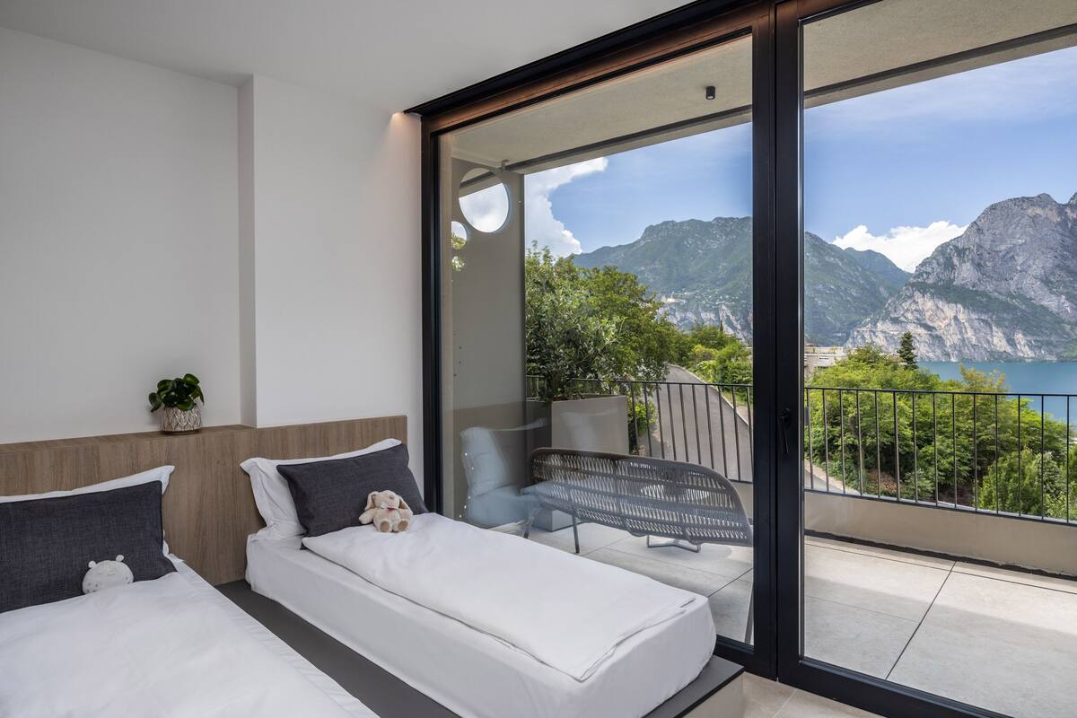Une chambre moderne dotée d’une grande porte-fenêtre coulissante donnant sur un balcon avec vue sur les montagnes.