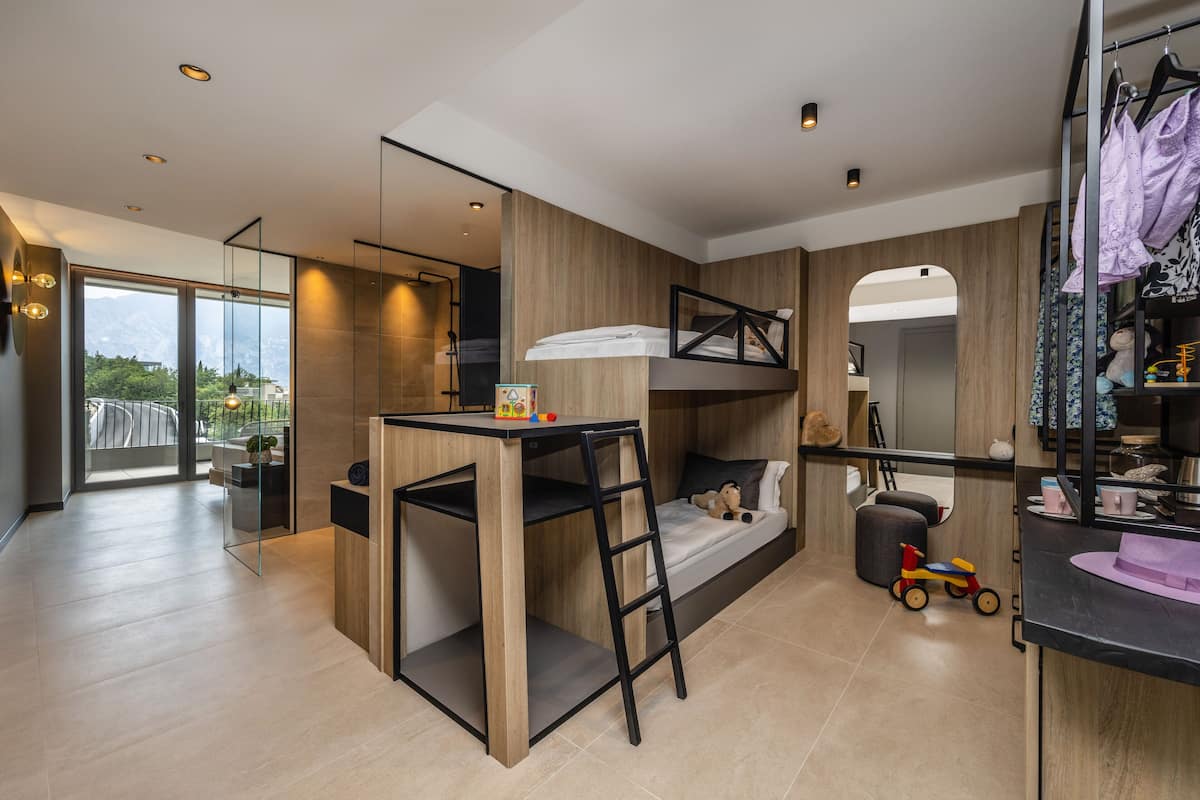 Une chambre moderne et compacte, équipée d’un lit superposé, d’un bureau et d’un petit coin salon.