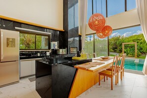 Una cocina moderna con una isla grande, horno empotrado y vista a una piscina.