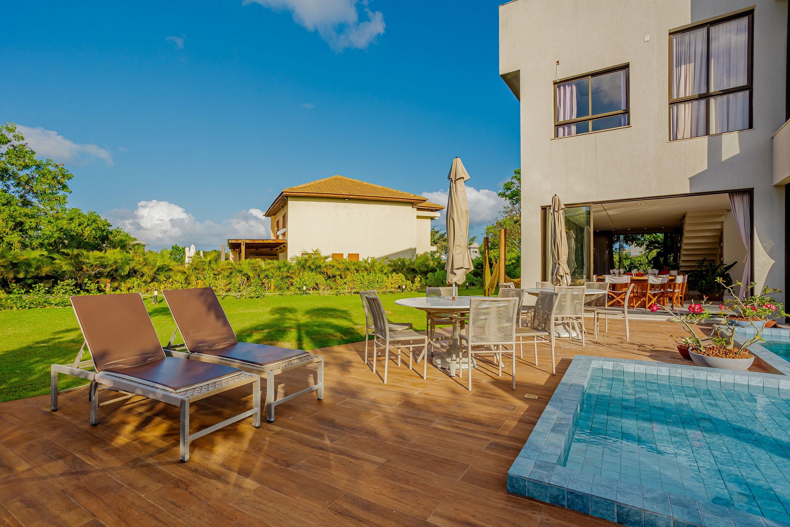Um pátio externo com piscina, espreguiçadeiras e área de refeições.