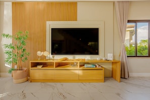 Ein modernes Wohnzimmer mit einem großen Flachbildfernseher, einer Holz-Unterhaltungseinrichtung und einem Bambusblatt in einem Topf.
