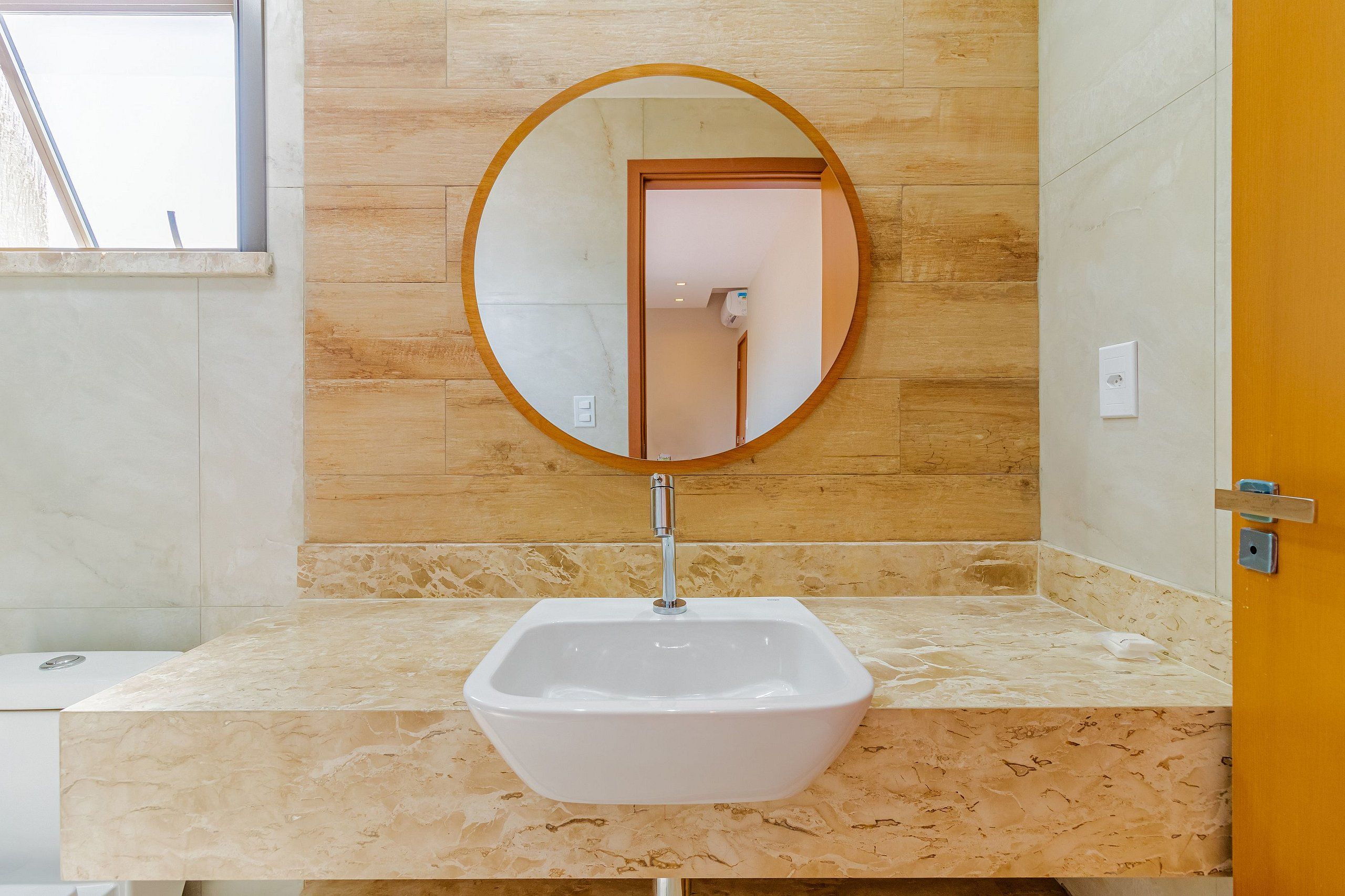 Ein Badezimmer mit einem runden Spiegel, einem Waschbecken und einer Holzwand.