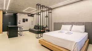 Ett modernt hotellrum med en stor säng, ett skrivbord och en sittgrupp.