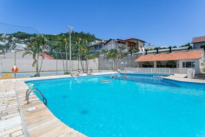 Une piscine entourée d’une terrasse en bois, d’une clôture et de palmiers.