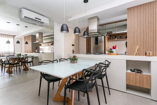Une cuisine moderne dotée d’un îlot central, de luminaires suspendus et d’appareils électroménagers intégrés.
