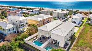 Zona residencial a la costa, amb cases, una piscina i una platja al fons.