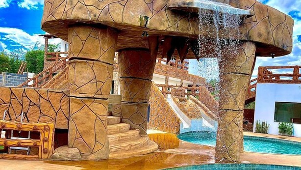 Zwembadgedeelte met een waterval, stenen architectuur en een helderblauw zwembad.