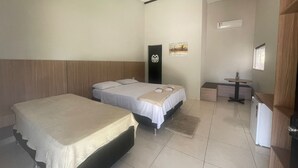 Een hotelkamer met twee bedden, een tafeltje, een koelkast en een schilderij aan de muur.